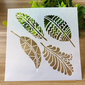 Close-up of a white plastic stencil with leaf and feather patterns on a wooden surface