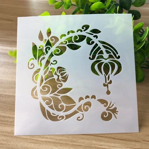 White PET stencil with hollow floral pattern for painting on a light wood background
