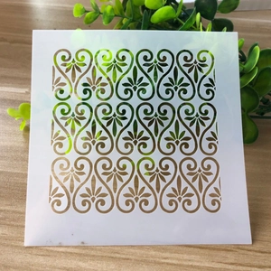 Close-up of a white square plastic stencil with elegant镂空floral heart patterns for DIY art