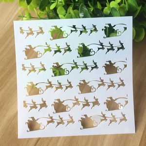 Detail of white PET Christmas stencils with reindeer and Santa Claus on wooden surface