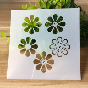 Close-up of white flexible plastic stencil featuring five distinct daisy flower patterns