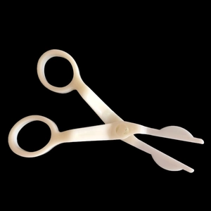 White plastic cake flower lifter tool for transferring cream decorations shown on black back