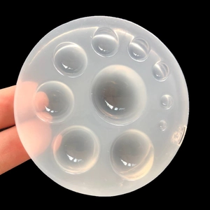 Macro detail of a clear silicone mold featuring various sized hemisphere cavities for resin
