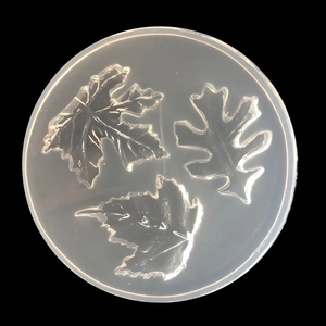 Macro detail of a clear silicone mold featuring three distinct leaf patterns for DIY resin crafts