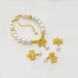 Detalle de dijes de mariposa dorados y pulsera de perlas blancas con espaciadores