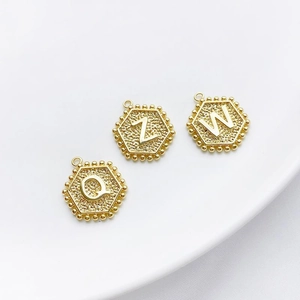 Macro-opname van 14K vergulde zeshoekige hangers met letters Q Z W en korrelige textuur