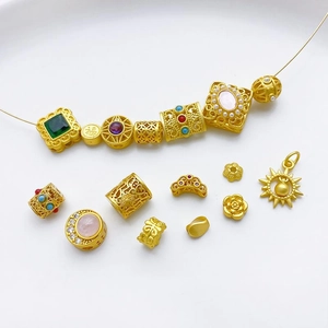 Detalle de cuentas de filigrana dorada y dijes para creación de joyas artesanales