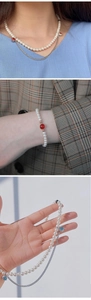 Detail of elegant shell pearl necklace set with red and blue gemstone accents
