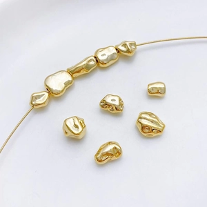 Vista macro de cuentas irregulares bañadas en oro de 14K con textura de metal líquido