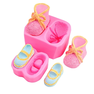 Detail of pink silicone mold with finished baby shoe models and intricate textures
