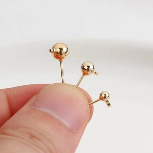 Detailed view of 14K gold plated ball stud earrings with loop held between fingers