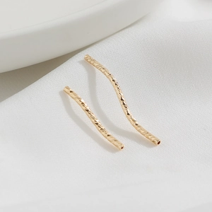 Dettaglio di perline a tubo curvo riempite in oro 14K con superficie sfaccettata per gioielli