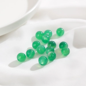 Makroaufnahme grüner, lichtdurchlässiger Achat-Rundperlen mit glatten Löchern für DIY-Schmuck