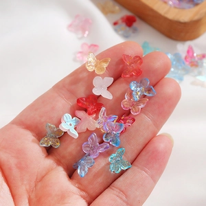 Macro view of colorful glass butterfly beads for DIY jewelry held in a palm
