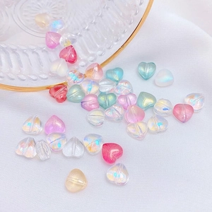 Detailed view of iridescent heart-shaped glass beads scattered on a textured white fabric