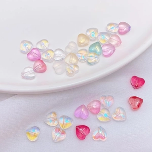 Macro shot of colorful heart glass beads for DIY jewelry making on white ceramic background
