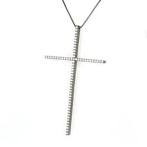 Macro detail of a gunmetal box chain with a slim cross pendant pavé-set with white zircons
