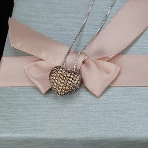 Nahaufnahme des Herzanhängers mit braunen Kristallen auf einer Geschenkbox mit Schleife