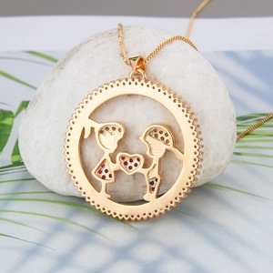 Close-up of gold hollow pendant with diamond-encrusted boy and girl charms on white stone
