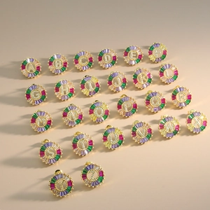 Makroansicht der Buchstaben-Ohrstecker mit bunten Steinen und funkelnden Pavé-Buchstaben