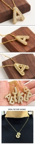 Detail of gold-plated balloon letter necklace with zircon pavé and hollow heart back