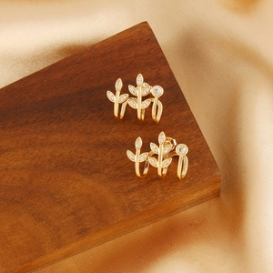 Leaf-shaped 18k gold plated stud earrings with sparkling diamonds on silk background