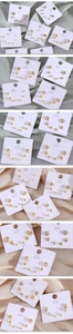 Dettaglio di un set di orecchini a lobo placcati in oro con cuori e stelle su carta