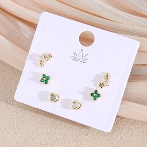 Nahaufnahme des 6er-Ohrring-Sets mit goldenem Stern, Herz und grüner Blume auf Satin