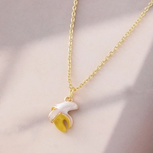 Kreative Banane-Halskette in Gold mit gelber Emaille auf lila Seidenhintergrund