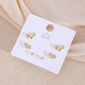 Drei Paar goldene Ohrstecker mit Herz-, Schleifen- und Zirkonia-Design auf Karte