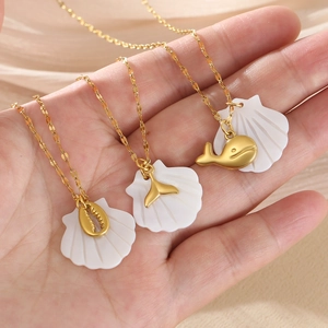 Detail of gold starfish and shell necklaces with white scallop accents on hand