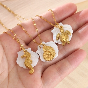 Detail of gold starfish and turtle pendants with shell inlay on delicate chains