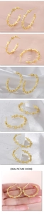 Détails macro de boucles d'oreilles créoles dorées avec croix en zircon sur tissu