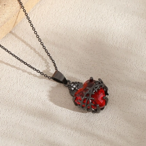 Halskette mit rotem Herz-Zirkon und schwarzem Dornenanhänger im Gothic-Stil auf Stein