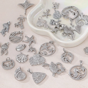 Details von silbernen Meeresanhängern mit Zirkonia auf einer weißen Muschelschale