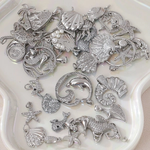 Meeres-Anhänger aus Silber mit Seestern, Delfin und Perlen auf einem Keramiktablett