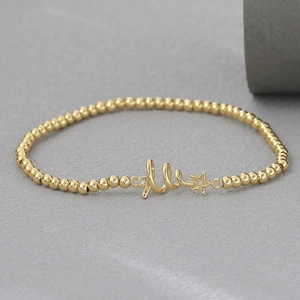 Detalle de pulsera de cuentas bañada en oro de 18k con colgante de estrella y cristales