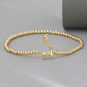 Vista de detalle de la pulsera bañada en oro de 18k con colgante de reno pulido y cuentas