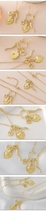 Detailed macro of 18k gold plated necklace featuring sacred heart and FE coin pendants