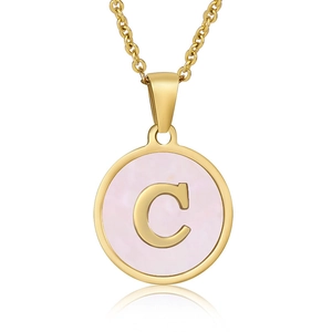 Detailed view of circular gold necklace pendant with letter C on pink shell background