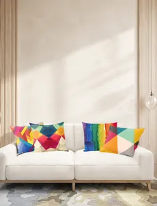 Detail van vier abstracte geometrische kussenslopen op een witte bank in de kamer