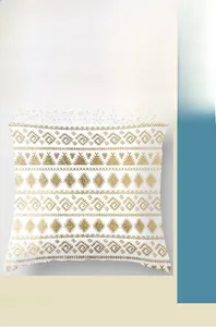 Close-up of peach skin fabric with gold geometric patterns on a white cushion cover
