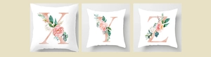 Detail view of white pillow covers with rose gold letters X Y Z and pink floral prints