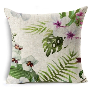 Detail shot of linen cushion cover showing tropical flower and green monstera leaf patterns