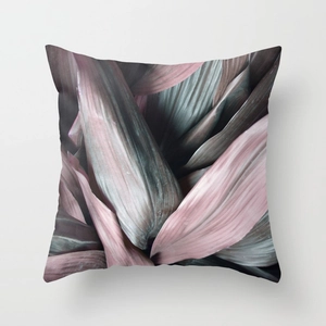 Detail of square pillow featuring elegant dusty pink and dark green tropical leaf prints