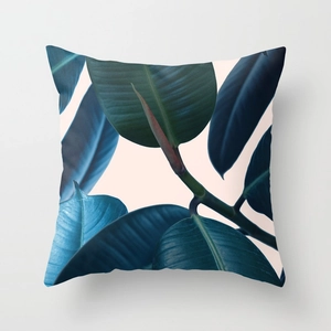 Detailed view of square peach skin pillow featuring green rubber tree leaf print