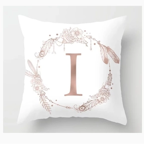 Detail of rose gold letter I with floral wreath design on a white square pillowcase