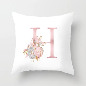 Macro shot of peach skin pillowcase showing letter H with floral patterns and gold accents