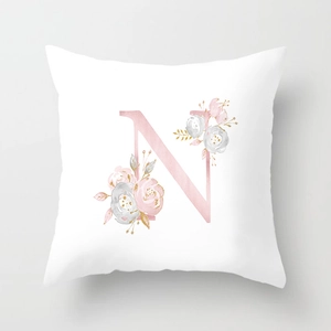 Close-up of peach skin fabric cushion cover with a floral pink letter N pattern