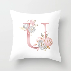 Close-up of rose gold letter U with watercolor flowers on soft peach skin pillowcase
